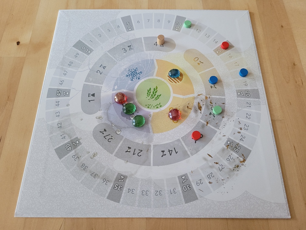 Der Spielplan von "Petrichor" mit konzentrischen Kreisen unterschiedlicher Nummerierung und Spielsteinen.