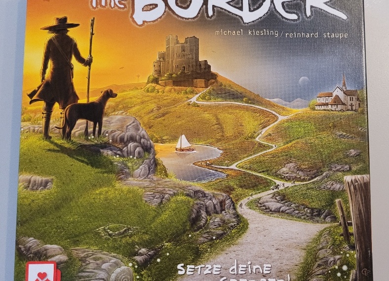 Das Cover von "The Border" auf dem eine kurvige Straße zu sehen ist. Am Rand steht ein Mann mit Stab und Hut, daneben sein Hund.