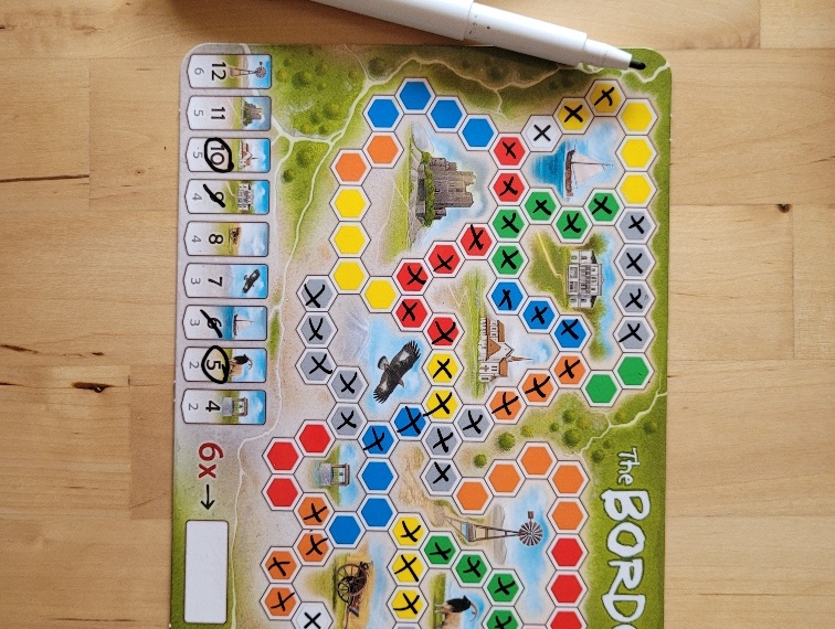 Das Spielertableau von "The Border" mit bereits einigen angekreuzten Grenzfeldern und Punkten sowie dem abwischbaren Stift.