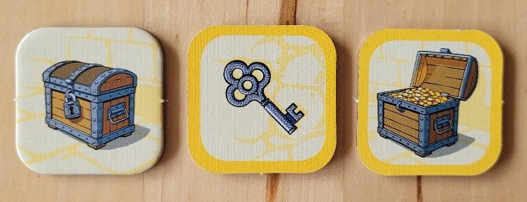 Drei Plättchen zeigen eine geschlossene und eine offene Schatztruhe mit Goldmünzen und einen Schlüssel.