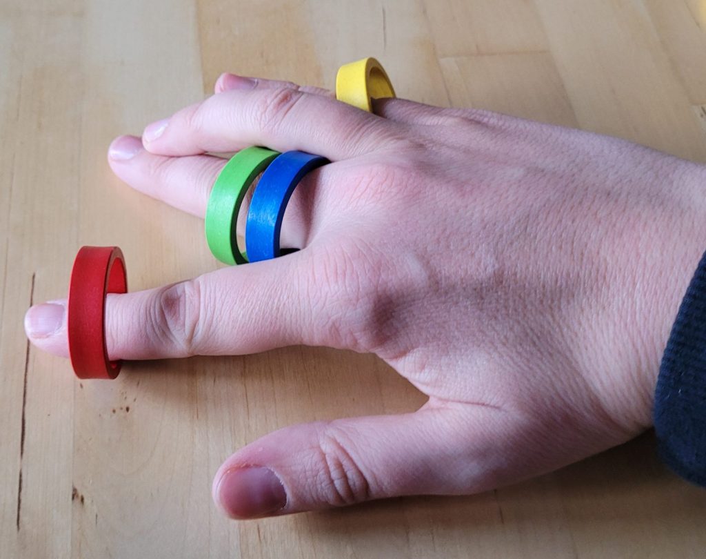 Eine Hand mit vier bunten Ringen aus "Oh My Ring!".