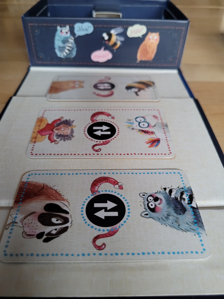 Drei Karten liegen vor der Spielschachtel von "Das NEINhorn". Es sind die Gegenwurm-Karten, bei denen immer zwei zu sagende Wörter vertauscht werden