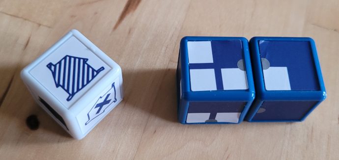 Ein weißer und zwei blaue Würfel zeigen unterschiedliche Symbole.