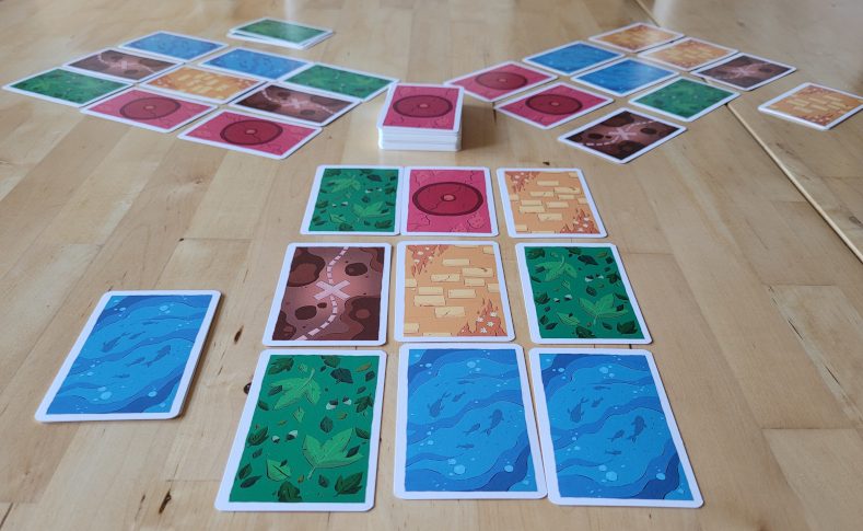 Für drei Spieler liegen je drei mal drei Karten bereit. Daneben die Ziehkarten und in der Mitte der Nachziehstapel.