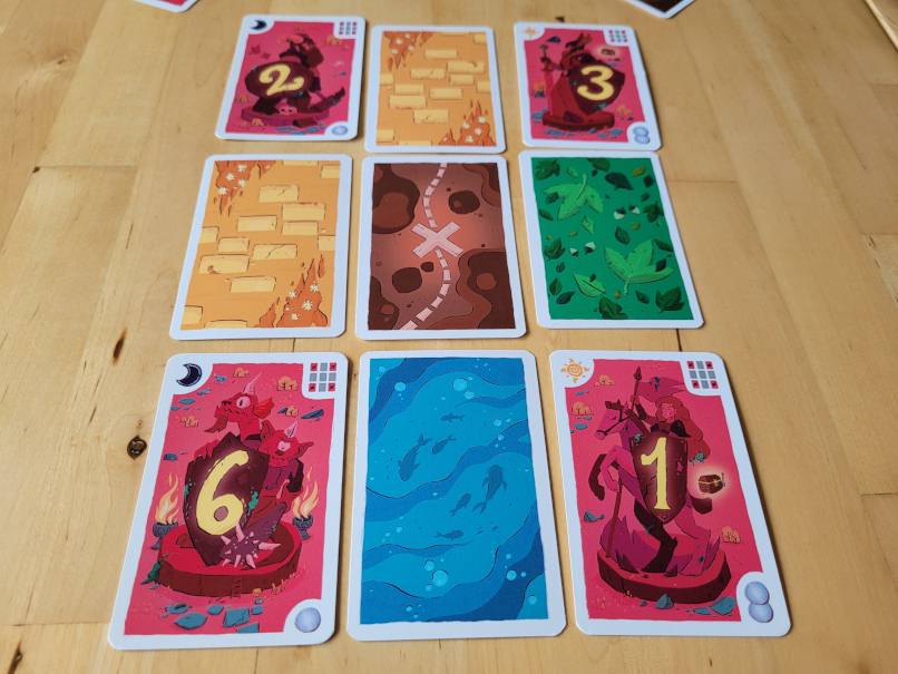 Vier Wächterkarten liegen in den Eckfelder der drei mal drei Karten.