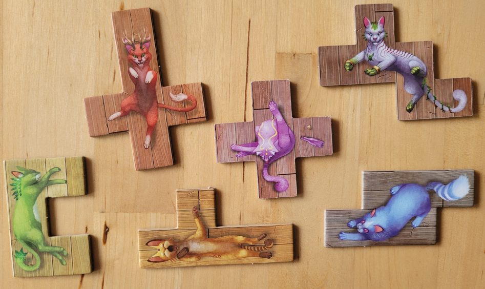 Sechs unterschiedlich geformte Plättchen mit bunten Katzen in kuriosen Positionen.