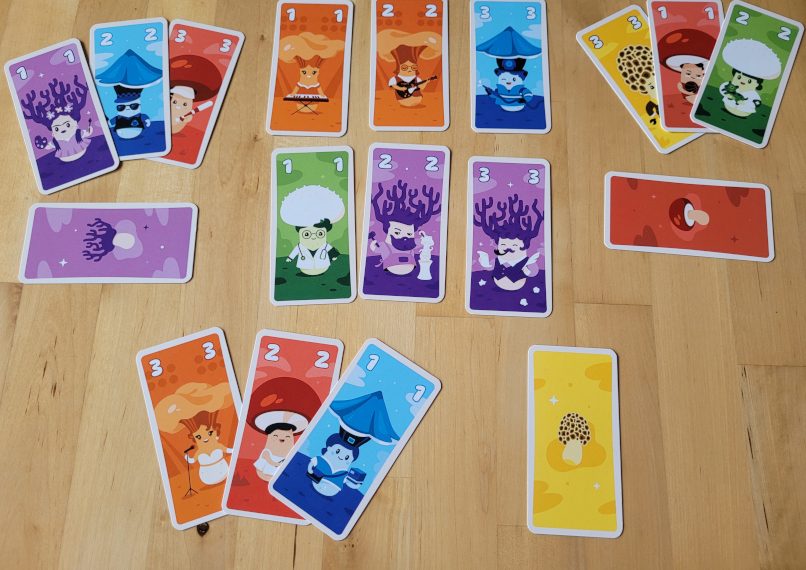Viele bunte Pilzkarten aus "Kinoko" liegen auf dem Tisch.