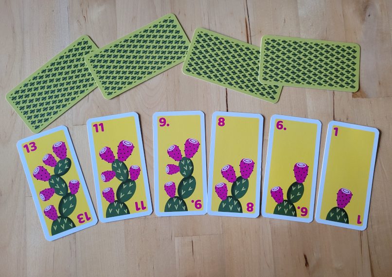 Sechs Karten mit Zahlen zwischen 1 und 13 und je einem Kaktus mit verschieden vielen Kaktusfeigen.