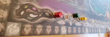 Auf dem Zauberstab auf dem Spielplan von "Witchstone" sitzen drei kleine Spielfiguren.