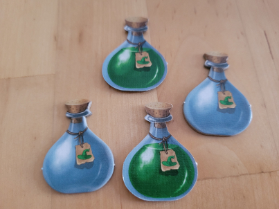 Vier Plättchen in Form von Zaubertrankflaschen mit Korken. Zwei sind leer, zwei sind gefüllt.
