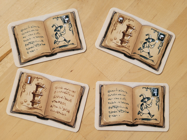 Vier Karten von "Die wandelnden Türme" zeigen Zauberer und Türme sowie Würfel oder Zahlen.