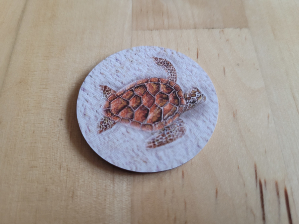 Ein rundes Plättchen zeigt eine Schildkröte.