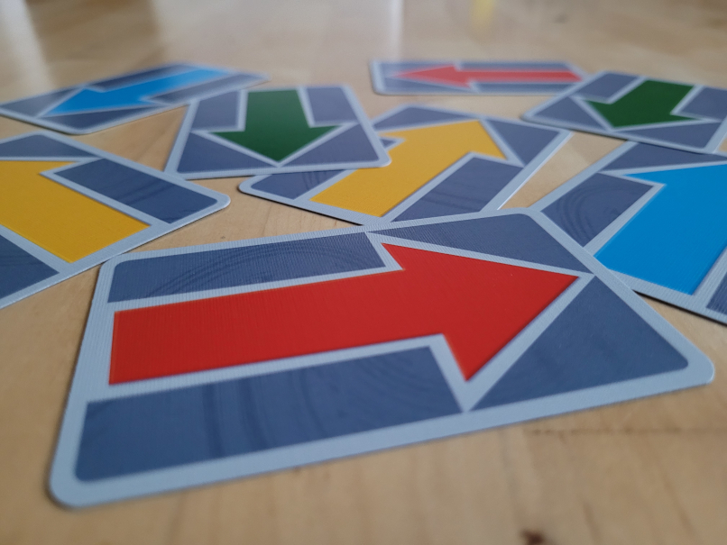 Je zwei gelbe, grüne, blaue und rote Pfeilkarten liegen verstreut auf einem Tisch.