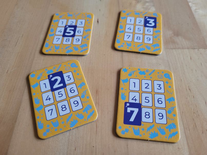 Vier Plättchen mit den Zahlen von eins bis neun. Je eine Zahl ist blau hervorgehoben.