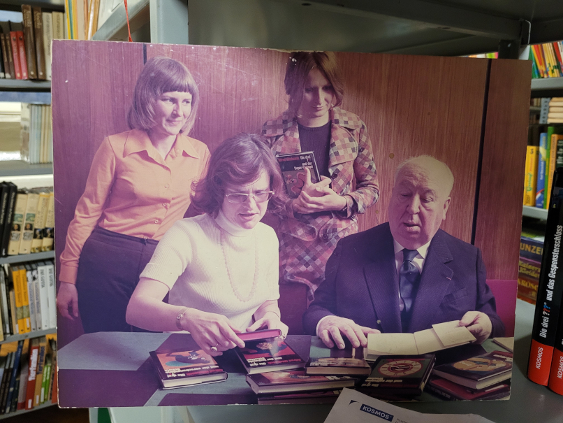 Ein Foto, auf dem drei Frauen neben Alfred Hitchcock sitzen.