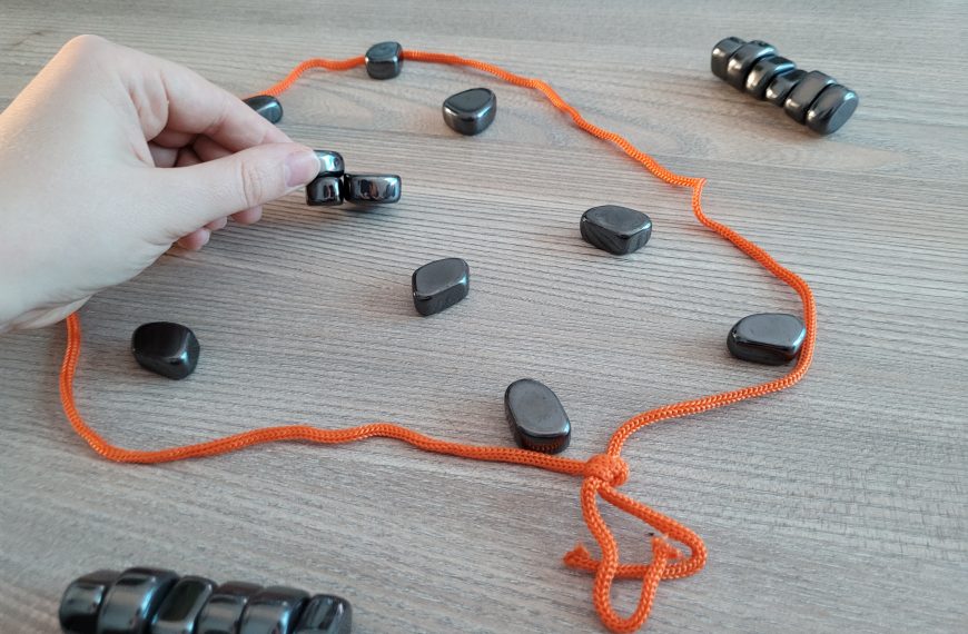 Eine Hand hält einen Spielstein, an den sich zwei andere Steine angezogen haben.