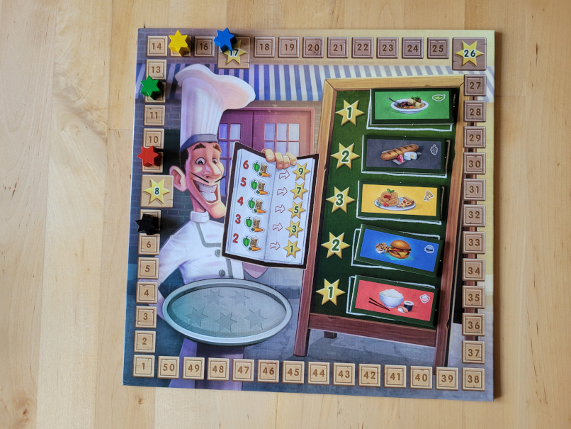 Der Spielplan zeigt einen Koch, eine Tafel mit verschiedenen Speisen und eine Zählleiste von eins bis 50.