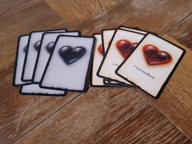 Zwei Kartenstapel aus "Adventure Games – Das Verlies" zeigen graue und rote Herzen.