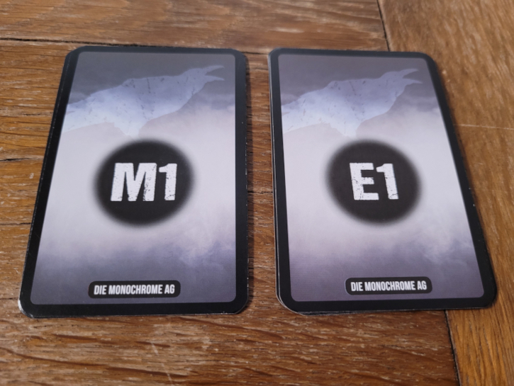 Zwei Kartenstapeln auf denen einmal "M1" und einmal "E1" zu lesen ist.