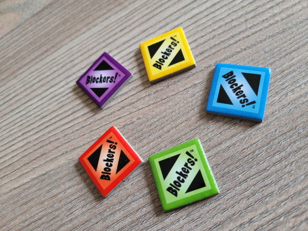 Fünf Jokerplättchen mit dem Aufdruck "Blockers!" in gelb, blau, rot, grün und lila.