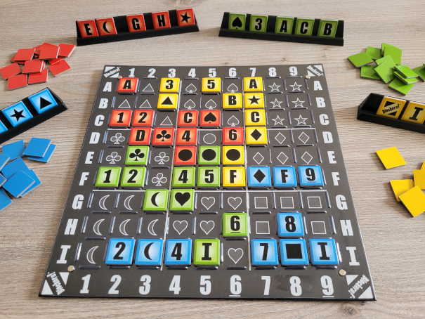 Auf dem Spielplan von "Blockers!" liegen Plättchen in vier Farben, die Bänkchen mit Plättchen und den verdeckten Haufen dabei stehen drumherum.