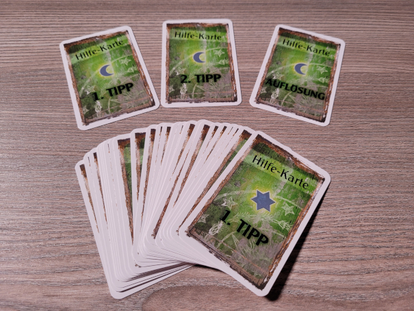 Eine Stapel und drei einzeln liegende "Hilfe-Karten" aus "Exit – das Spiel: Die Station im ewigen Eis".