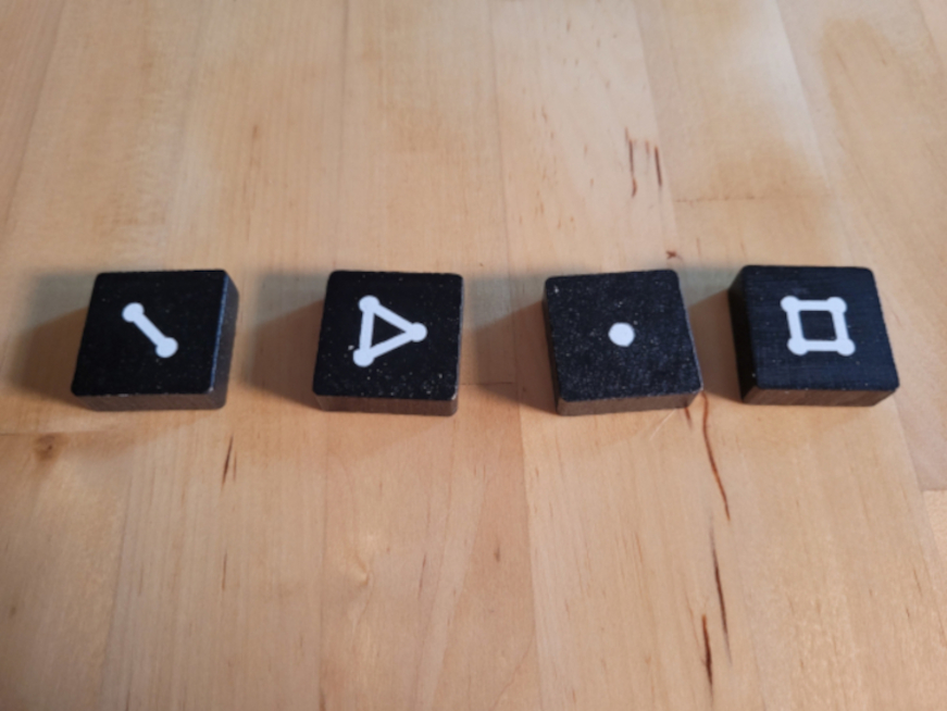 Vier schwarze Steine mit den Werten eins, zwei, drei und vier.