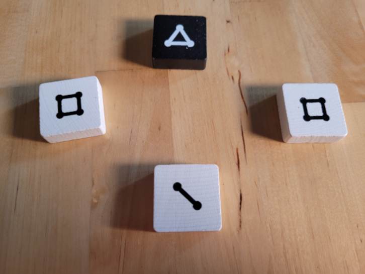 Drei weiße Steine mit den Werten vier, vier und eins und ein schwarzer Stein mit dem Wert drei.