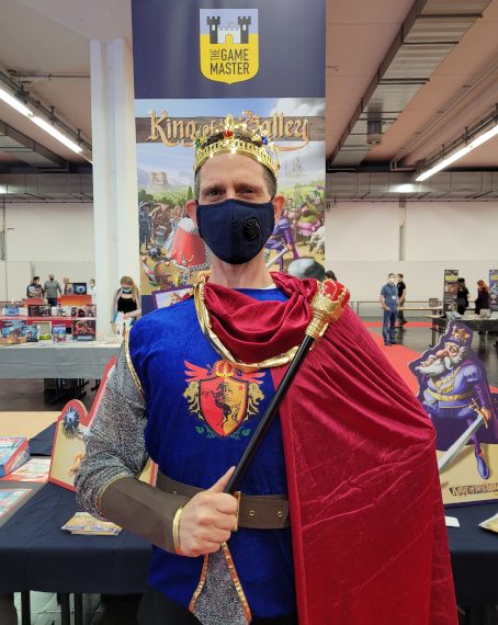Ein Mann in Königskostüm mit Krone, Zepter und Umhang vor dem Stand von "King of the Valley".
