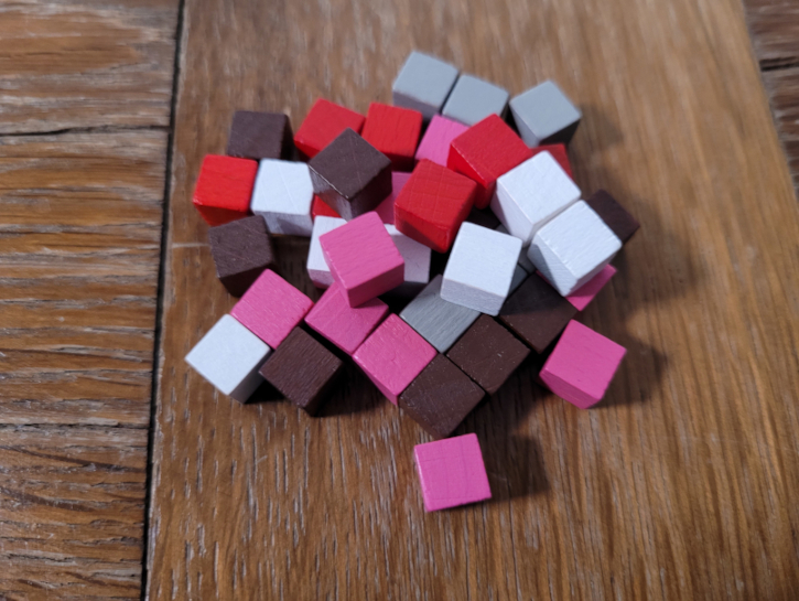 Ein Haufen kleiner Holzwürfel in Braun, Rot, Weiß, Grau und Pink.