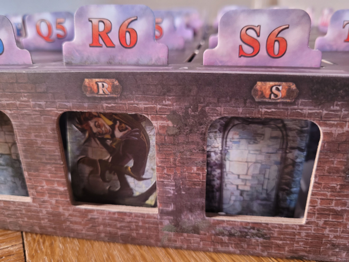 Öffnungen im Seitenrand der Spielschachtel von "Mystery House" zeigen eine Wand und einen Kobold.