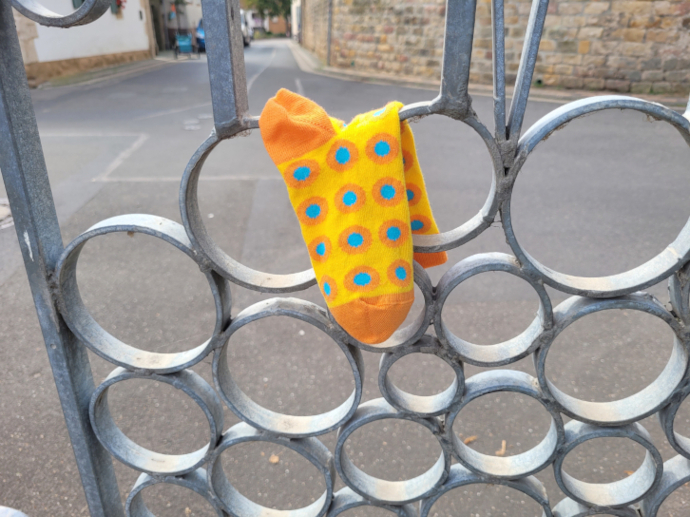 Die gelbe Socke mit blauen Punkten hängt in einem metallenen Tor.