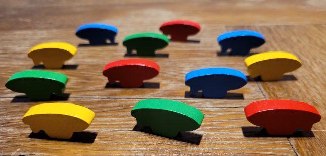 Zwölf Holzzeppelin-Spielfiguren, je drei in Blau, Gelb, Rot und Grün.