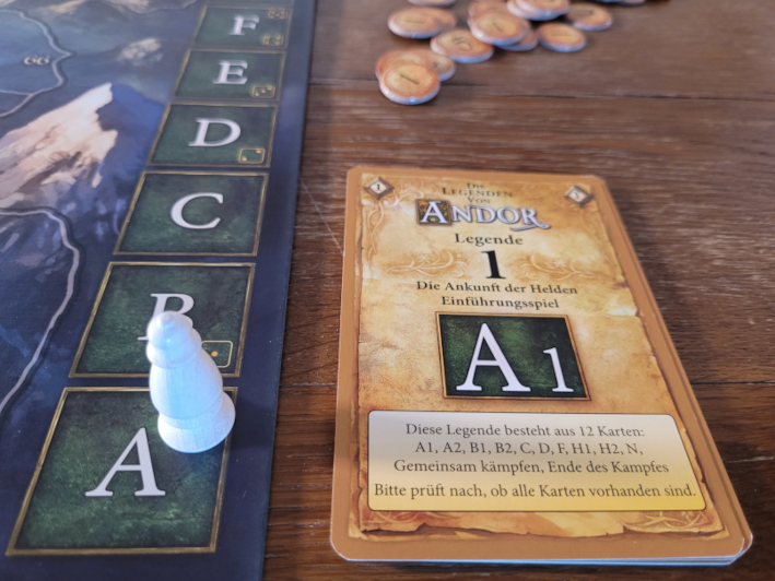 Die Legendenkarten aus "Die Legenden von Andor" liegen neben der Erzählerleiste auf dem Spielplan. Auf dem Buchstaben "A" steht die weiße Erzählerfigur.