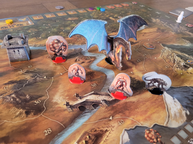 Verschiedene Monster, ein Drachen und ein Turm stehen auf dem Spielplan von "Die Legenden von Andor".