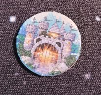 Eine runde Siegscheibe aus "Realm of Wonder" zeigt eine Burg, in deren vergittertem Tor ein helles Licht leuchtet.