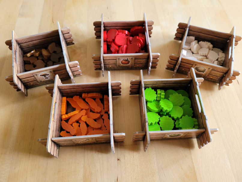 In fünf aus Karton zusammengesteckten Kisten, die wie aus Holz aussehen, liegen Tomaten, Blumenkohl, Salat, Pilze und Karotten aus Holz.