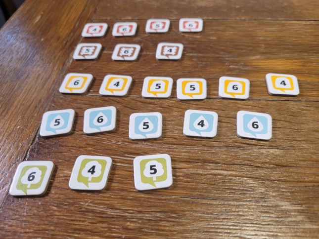 In fünf Reihen liegen Zahlenplättchen mit den Ziffern 4, 5 und 6 auf einem Tisch.