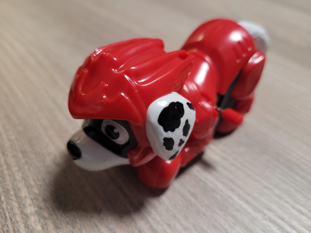 Eine Spielfigur, kleiner Hund, rote Uniform, roter Helm, schwarz-weiß gepunktete Ohren.