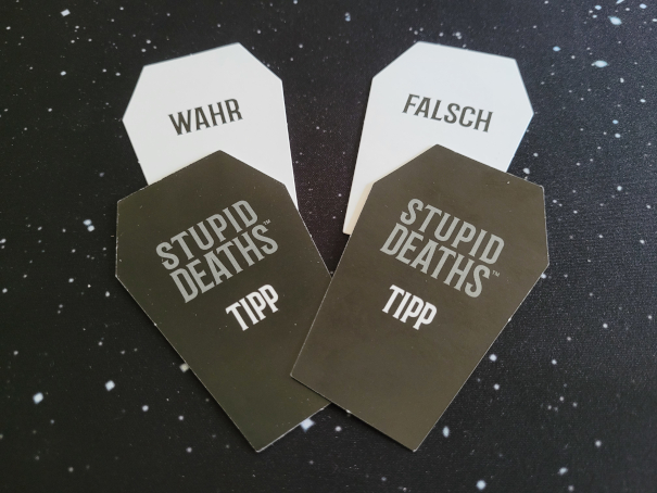 Vier Tippkarten. Zwei Rückseiten zeigen "Stupid Deaths – Tipp", je eine Vorderseite "wahr" und "falsch".