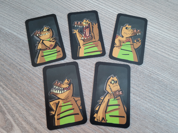 Fünf Karten mit einem Grimassen schneidenden Comic-Krokodil.