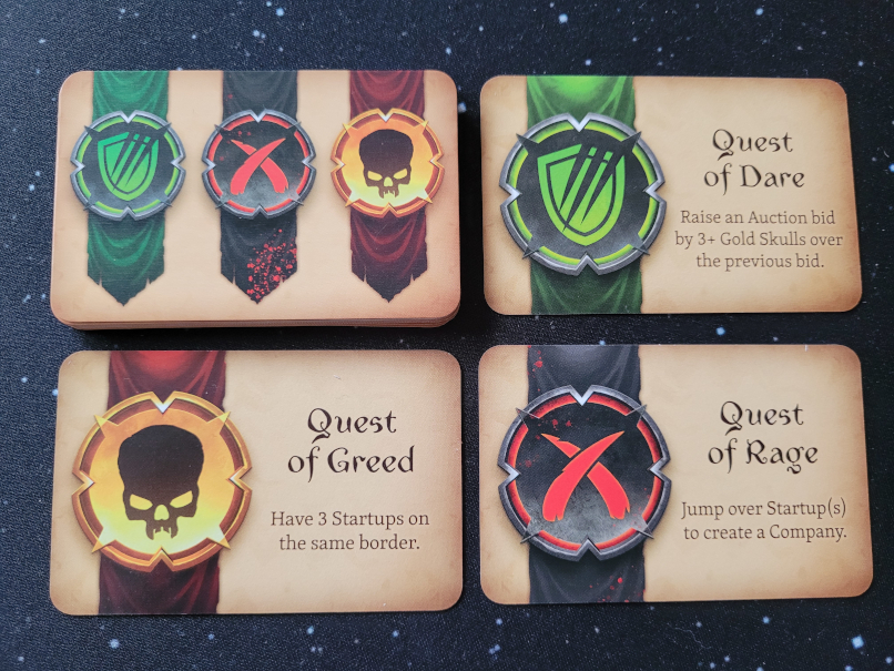 Ein Stapel Questkarten und je eine aufgedeckte Questkarte in Grün, Gelb und Rot.