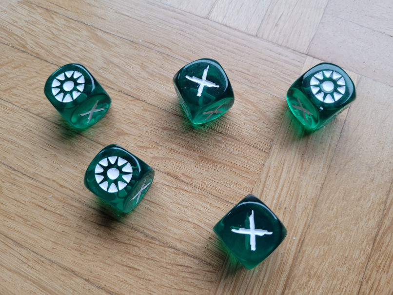 Fünf grüne Würfel, zwei zeigen ein X, drei eine Art Sternsymbol.