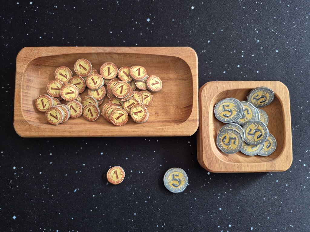 Münzplättchen mit den Werten eins und fünf in Holzschalen.