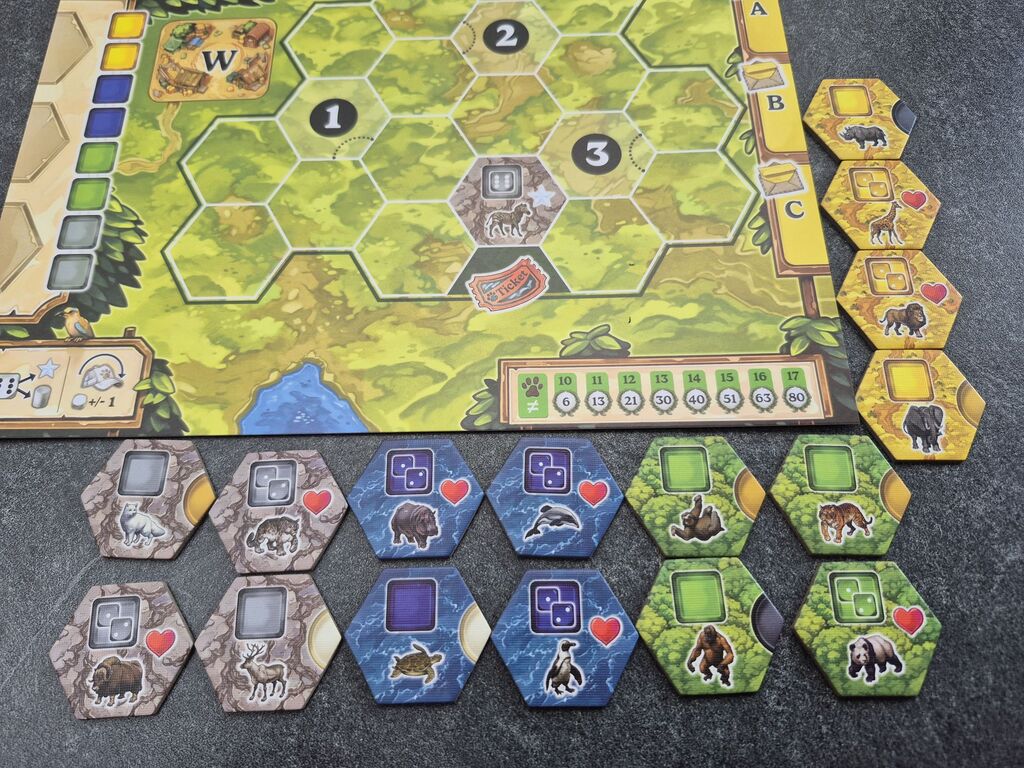Plättchen mit verschiedenen Tieren liegen um den Spielplan.