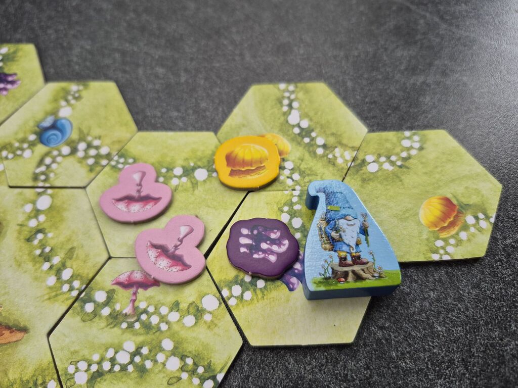 Pilzmarker liegen auf Plättchen neben der blauen Spielfigur.