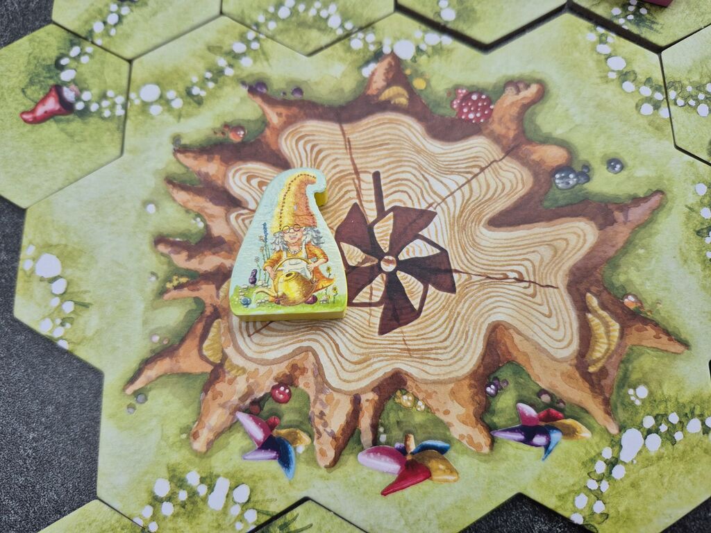 Die gelbe Spielfigur liegt auf dem Spielplanteil mit dem Baumstumpf.
