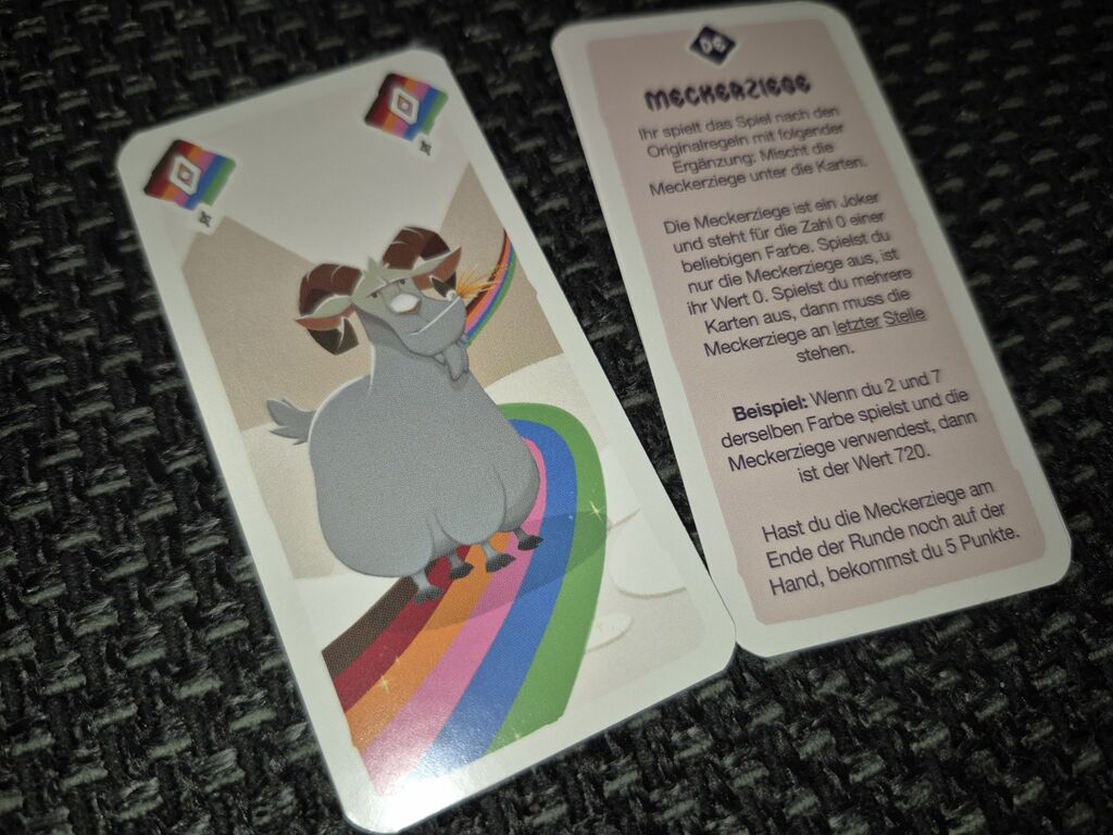 Eine Karte mit einem Regenbogen und einer grauen Ziege. Daneben eine Karte mit Text.