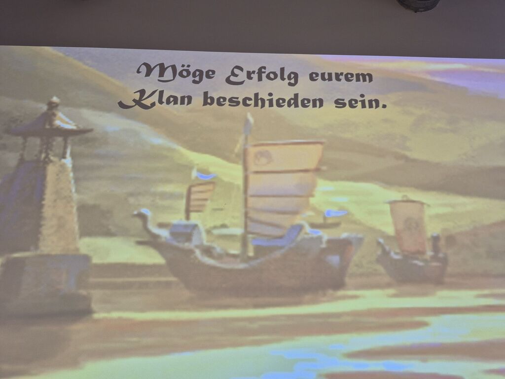 Eine Präsentationsfolie mit Schiffe und dem Text "Möge Erfolg eurem Klan beschieden sein."
