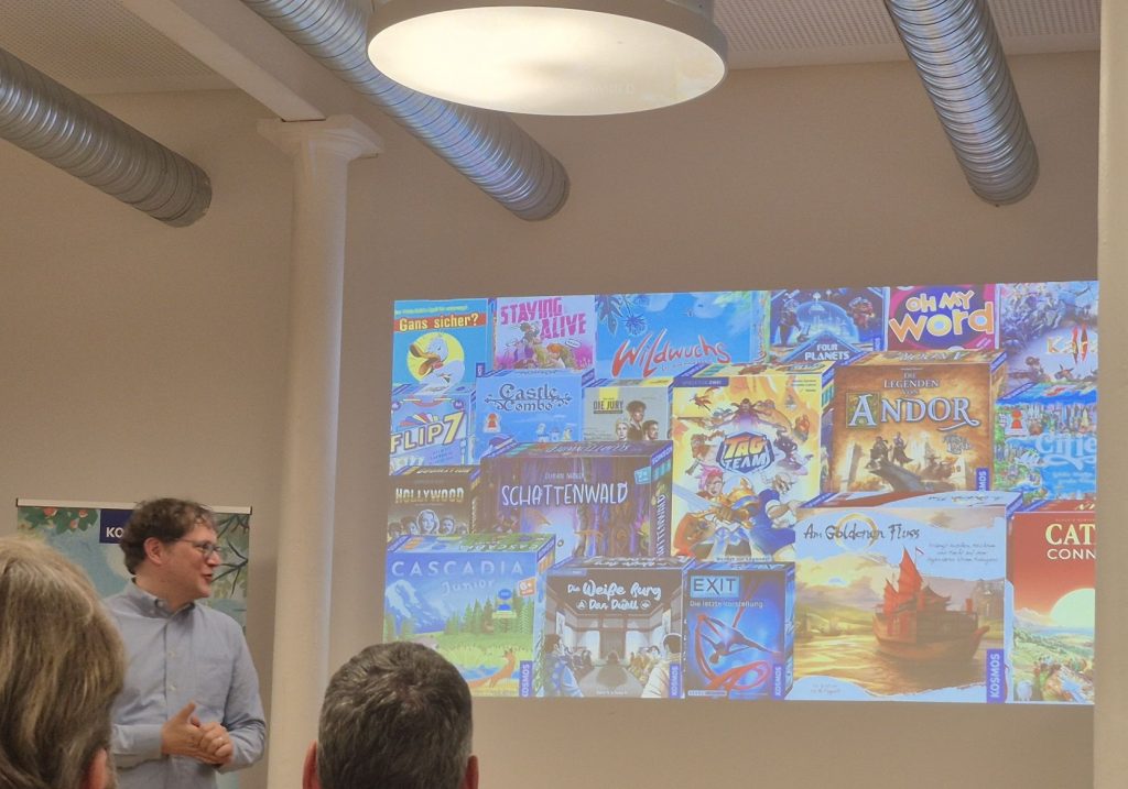 Ein Mann vor einer Präsentation mit vielen Spielschachteln.